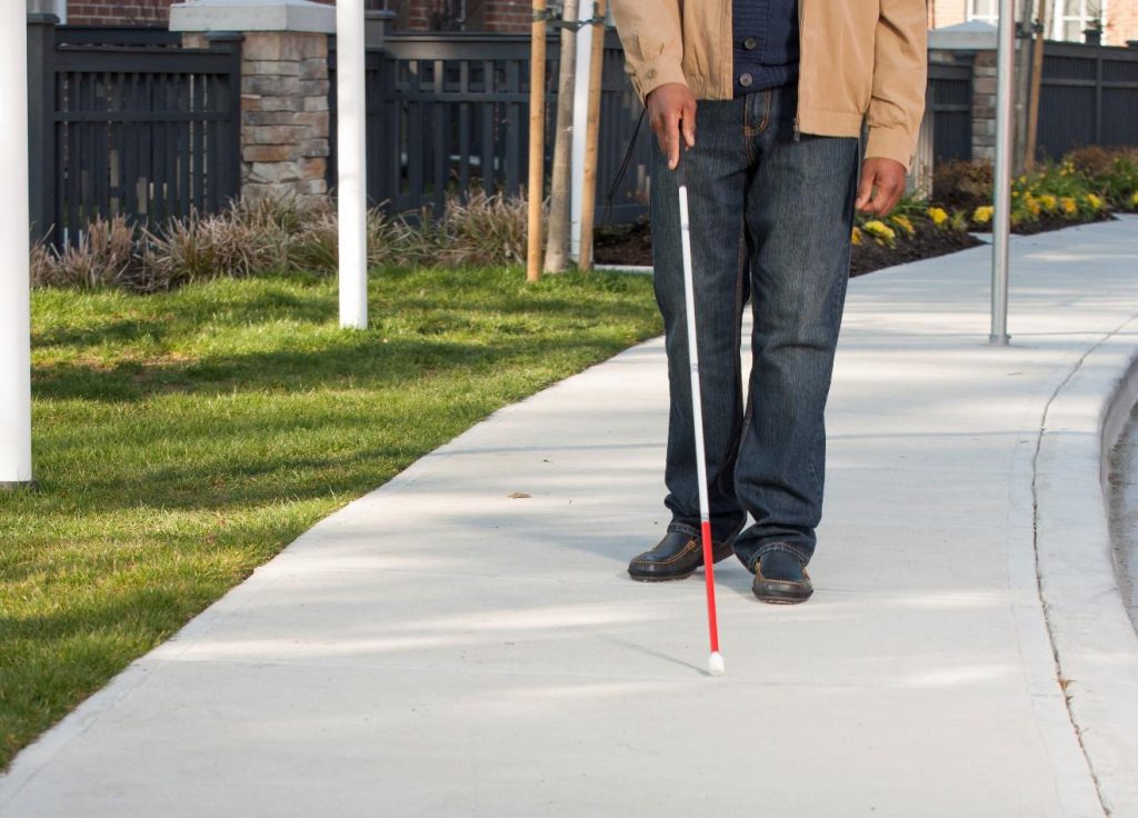 Picture of a man walking down a sidewalk with a cane